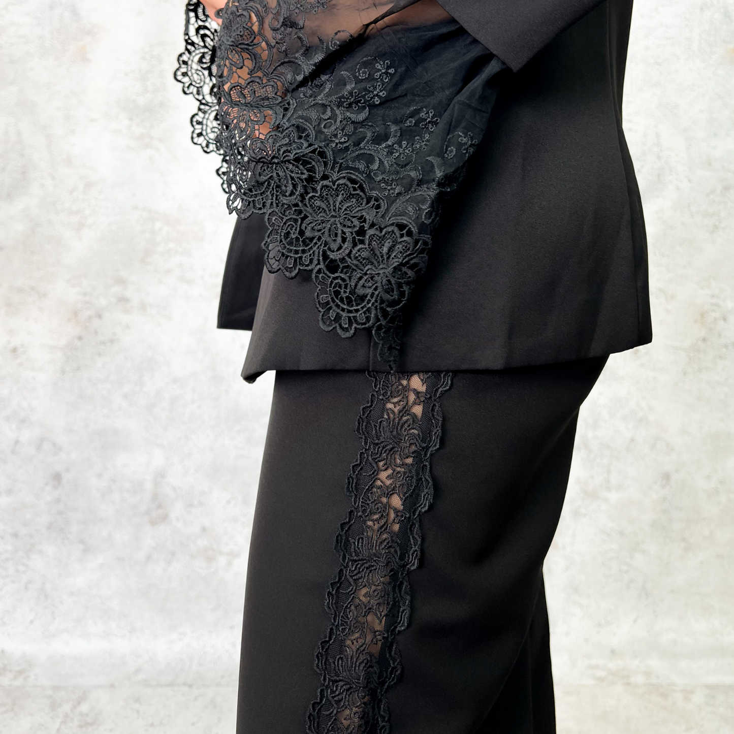 Traje sastre negro con detalles de encaje en mangas y costados.