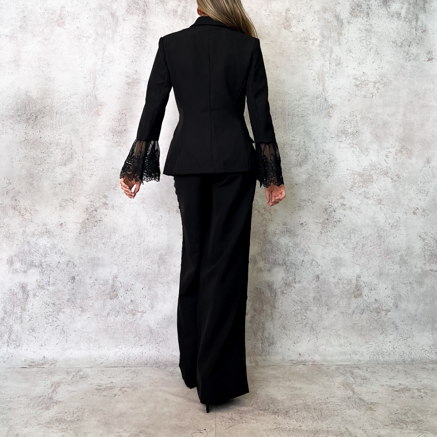 Traje sastre negro con detalles de encaje en mangas y costados.