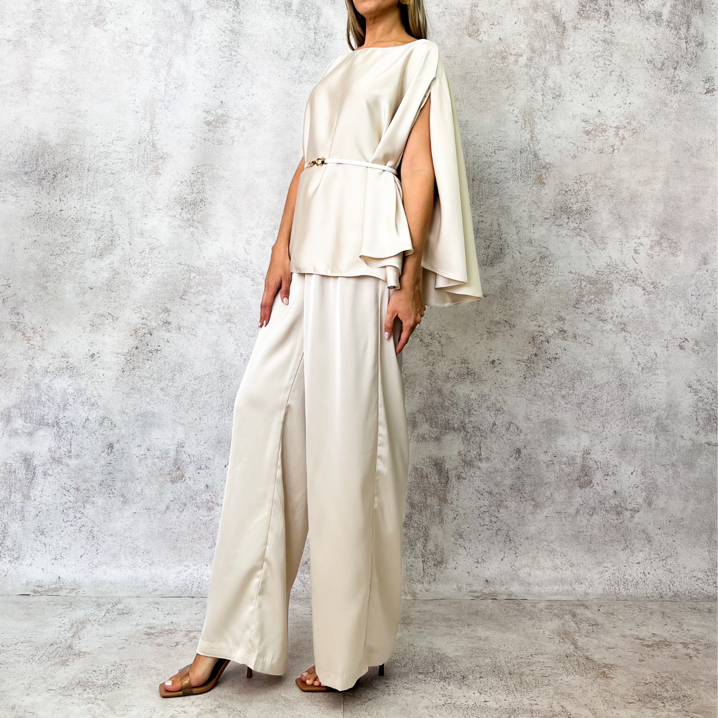 Conjunto beige con cinturón metálico.