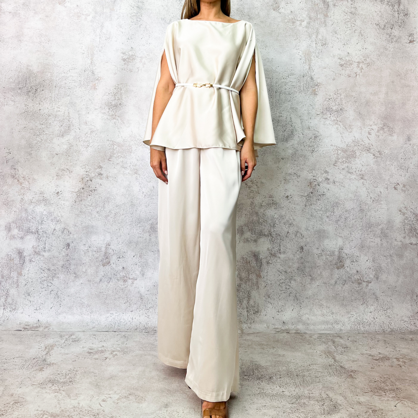 Conjunto beige con cinturón metálico.