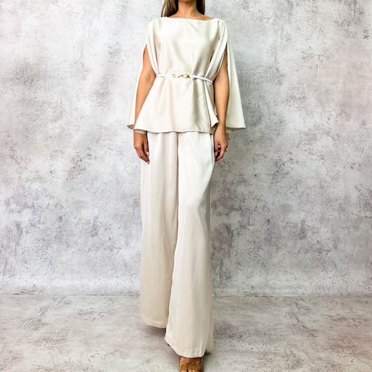 Conjunto beige con cinturón metálico.