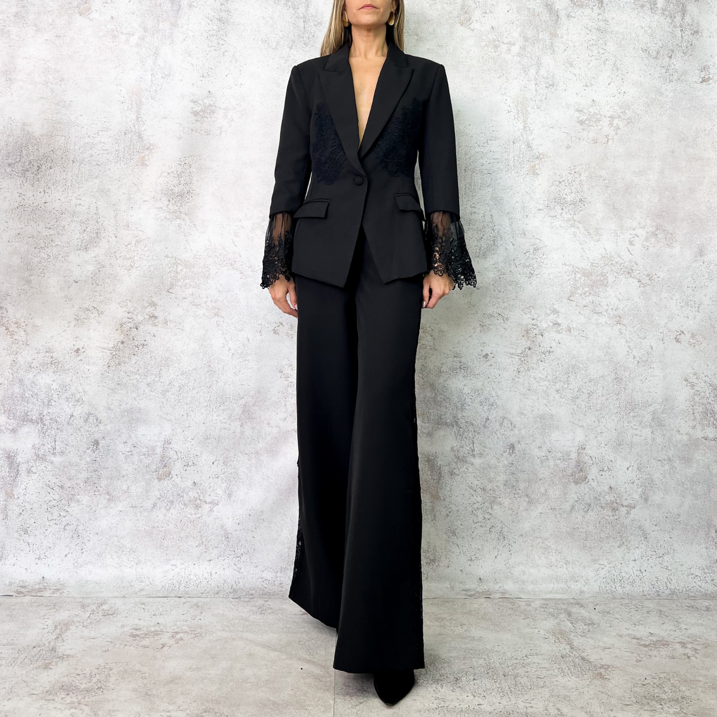 Traje sastre negro con detalles de encaje en mangas y costados.
