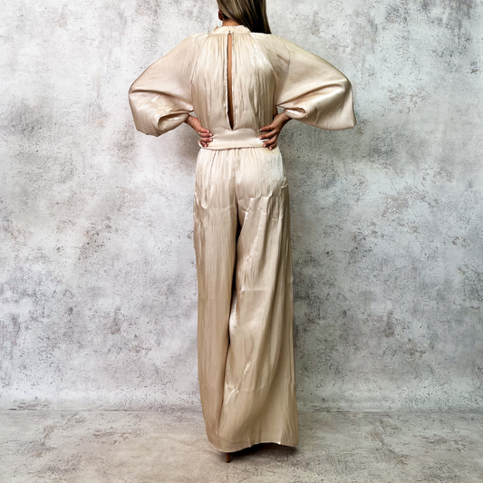 Jumpsuit beige satinado con mangas globo y cinturón.