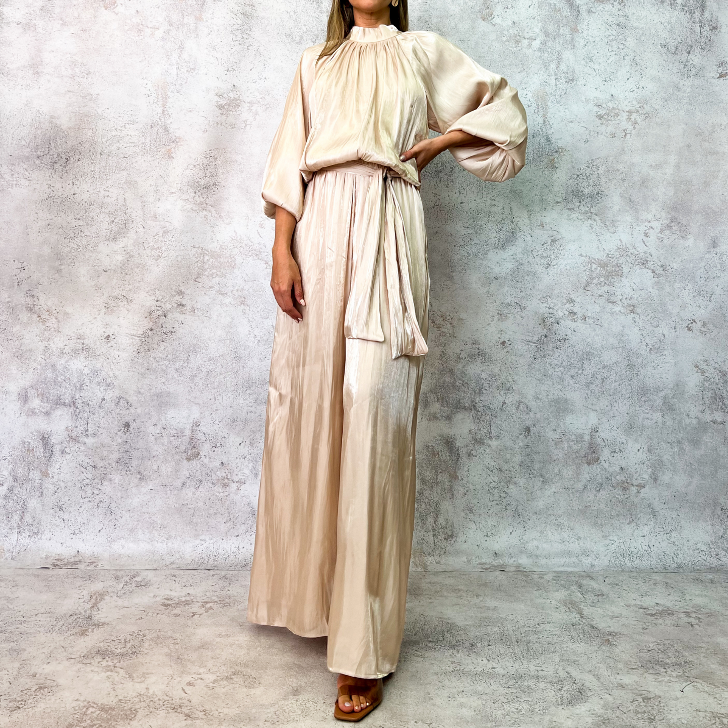 Jumpsuit beige satinado con mangas globo y cinturón.