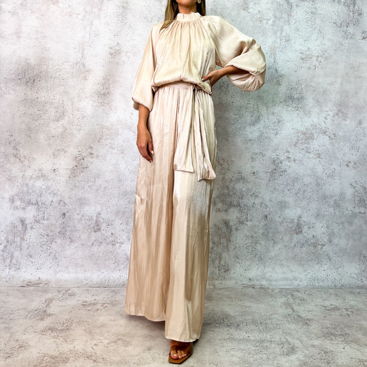 Jumpsuit beige satinado con mangas globo y cinturón.