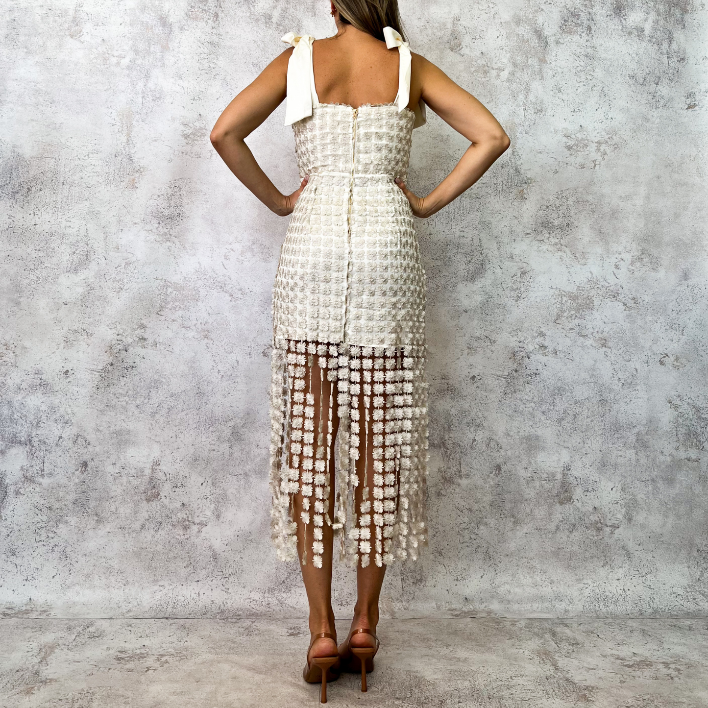 Vestido midi beige con encaje floral y flequillos.